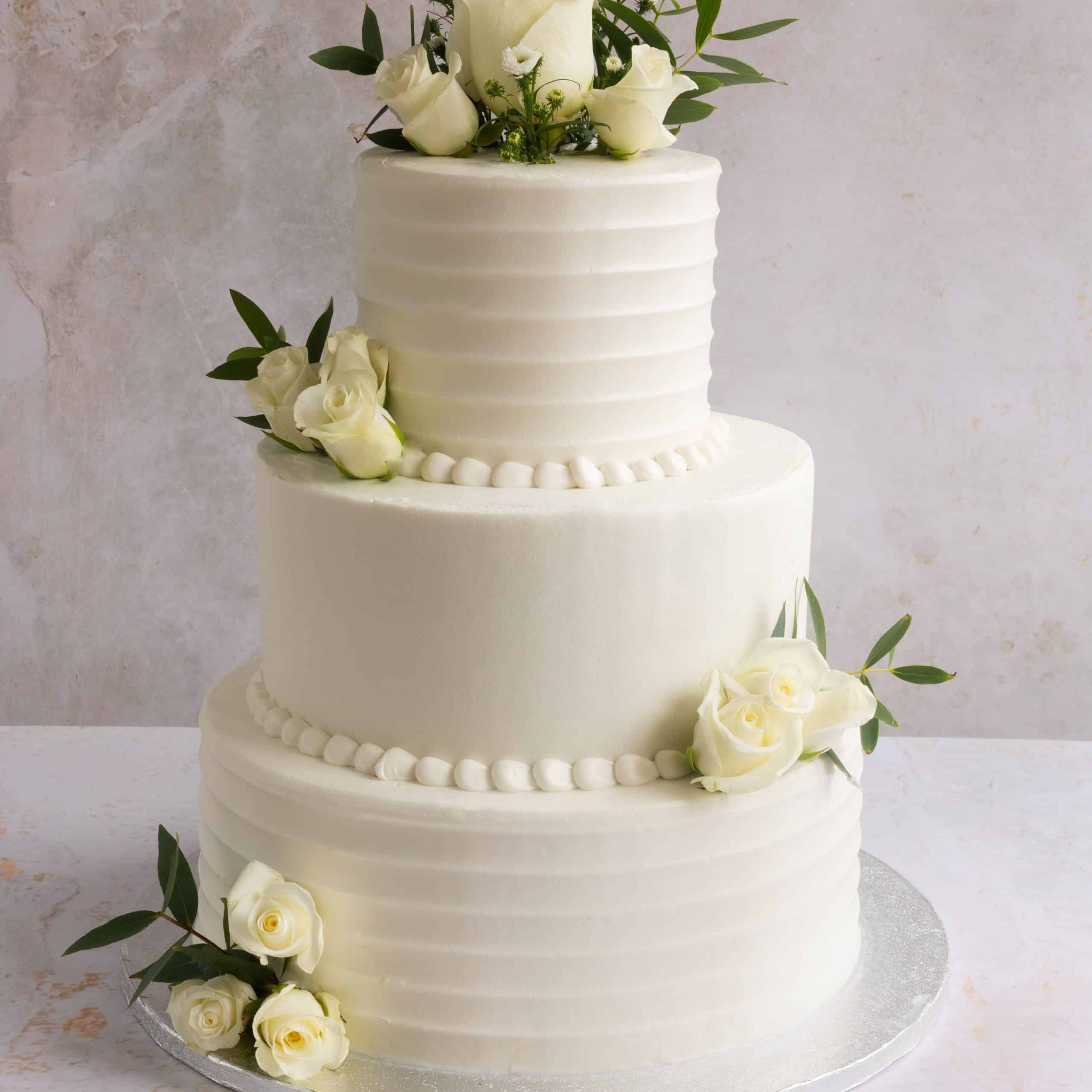 Tarta de boda de tres pisos con flores blancas